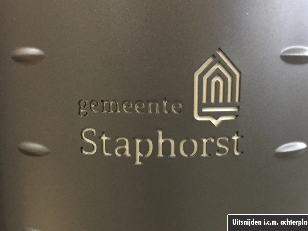 Uitgesneden logo in deurpaneel van de afvalbak